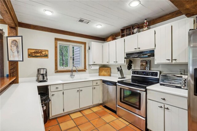 kitchen featuring appliances with stainless steel finishes, light tile patterned flooring, white cabinetry, and sink