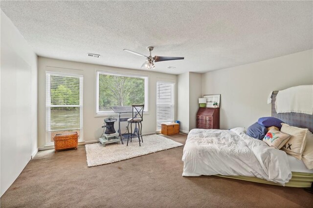 bedroom with ceiling fan, carpet flooring, and a textured ceiling