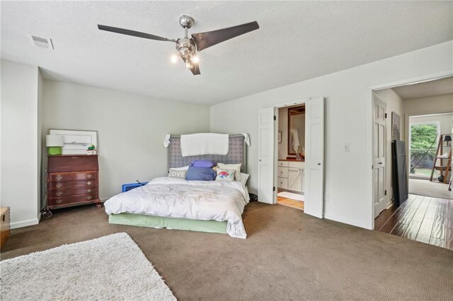 carpeted bedroom with ensuite bath, a textured ceiling, and ceiling fan