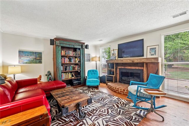 living room with a wealth of natural light, hardwood / wood-style floors, a brick fireplace, and a textured ceiling