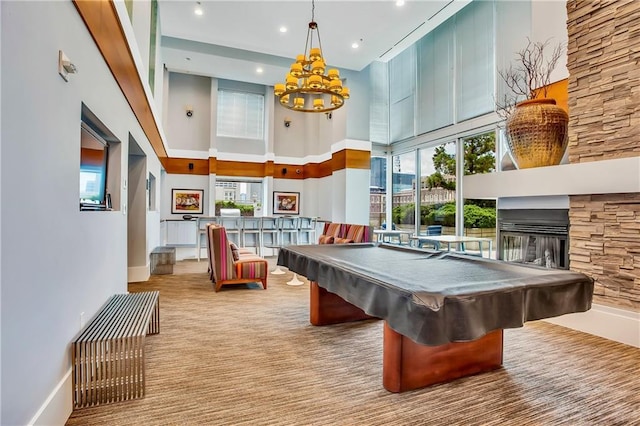 recreation room with light colored carpet, billiards, a stone fireplace, and a high ceiling