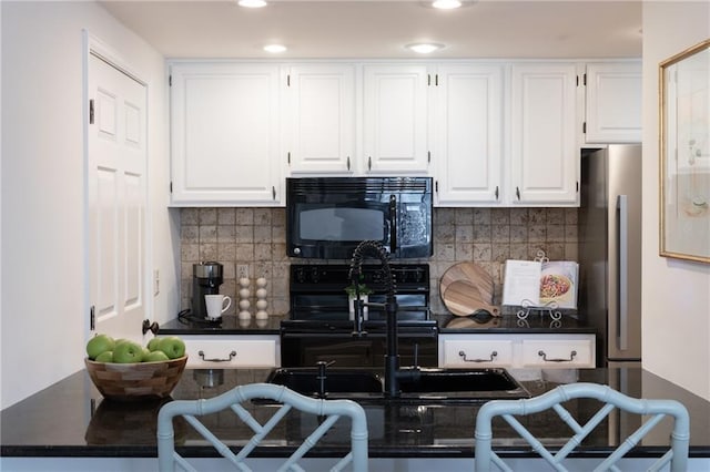 kitchen featuring dark countertops, stove, freestanding refrigerator, white cabinets, and black microwave