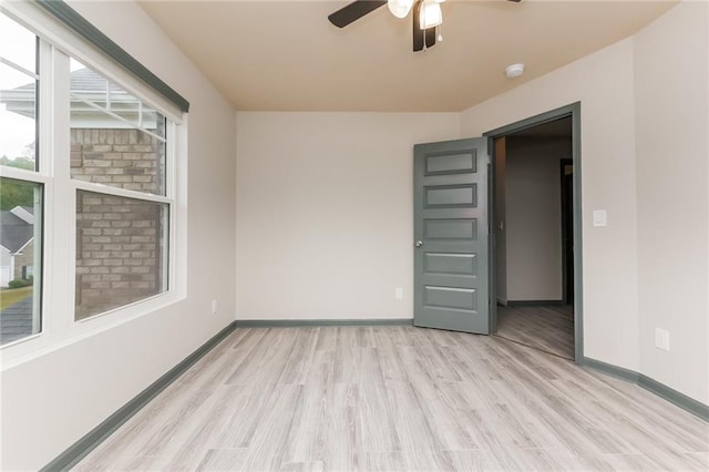 empty room with ceiling fan and light hardwood / wood-style flooring