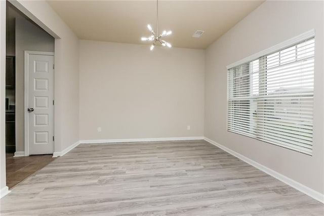 spare room with light hardwood / wood-style flooring and a notable chandelier