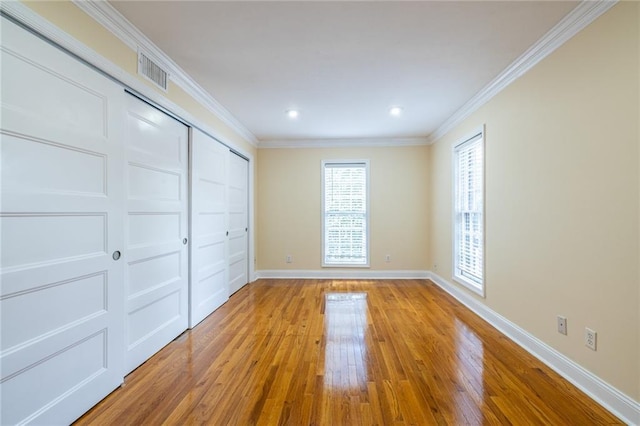 unfurnished bedroom featuring wood-type flooring, baseboards, ornamental molding, a closet, and recessed lighting