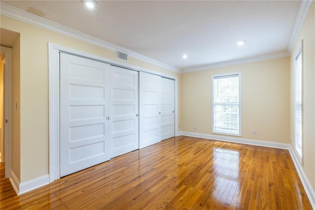 unfurnished bedroom featuring hardwood / wood-style flooring, baseboards, ornamental molding, a closet, and recessed lighting