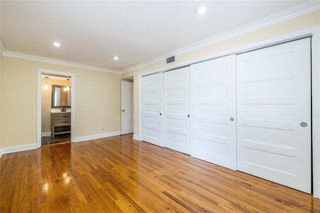 unfurnished bedroom with light wood-style floors, ornamental molding, baseboards, a closet, and recessed lighting