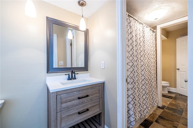 bathroom featuring toilet, stone finish floors, and vanity