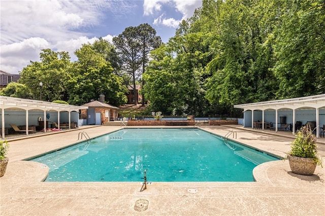 community pool featuring a patio area and view of scattered trees