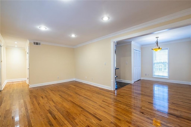 spare room featuring wood finished floors, baseboards, crown molding, and recessed lighting