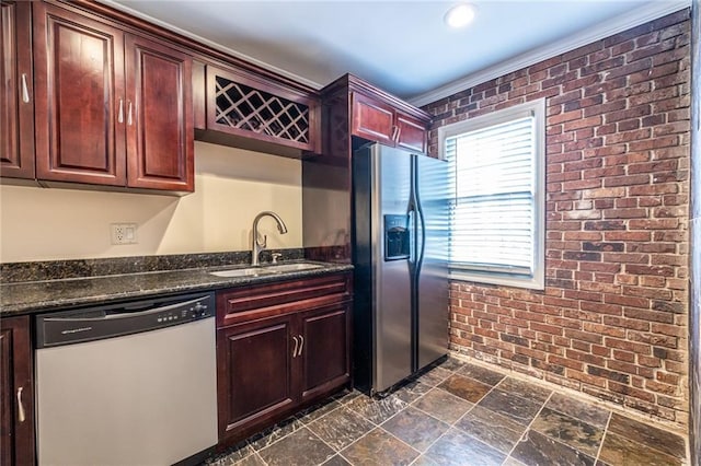 kitchen with dishwasher, stainless steel refrigerator with ice dispenser, a sink, brick wall, and dark stone finish floors