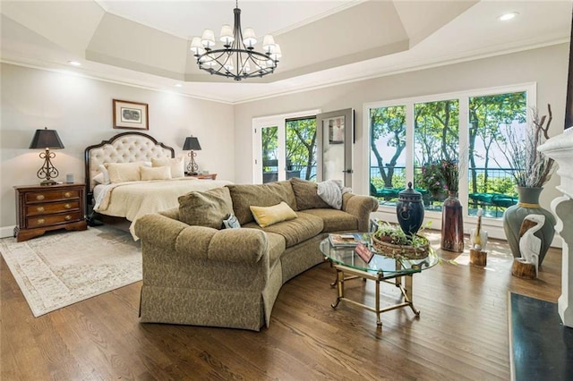 bedroom featuring a raised ceiling, ornamental molding, dark wood-style floors, and a chandelier