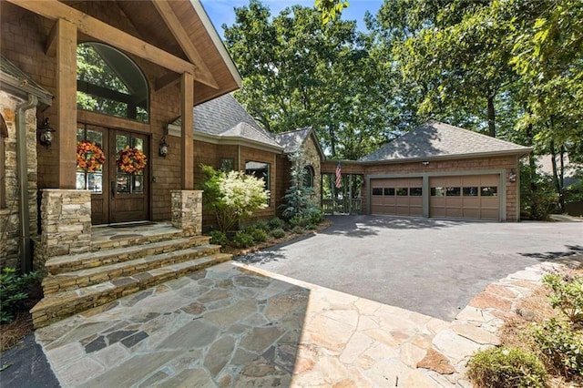 exterior space with french doors, a garage, driveway, and a shingled roof