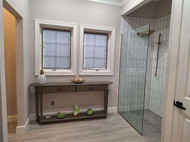 bathroom with wood finish floors, baseboards, and walk in shower