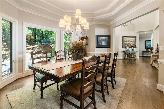 dining room with crown molding, wood finished floors, a wealth of natural light, and a chandelier