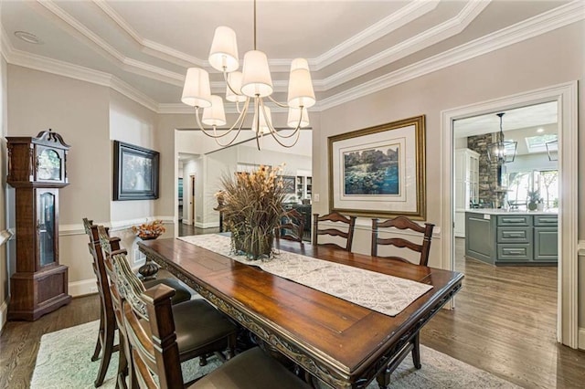 dining area with wood finished floors, a raised ceiling, a chandelier, and crown molding