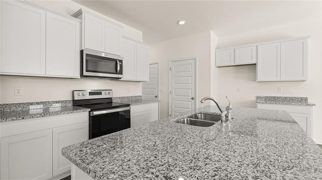 kitchen with stainless steel appliances, sink, a center island with sink, and white cabinets