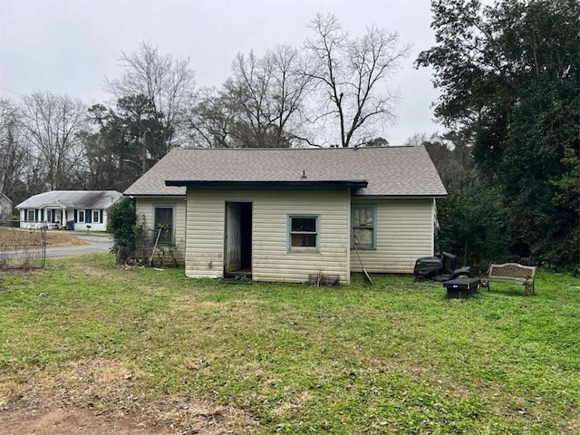 rear view of house with an outdoor fire pit and a yard