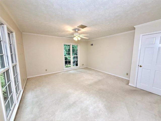 spare room featuring a ceiling fan, baseboards, a textured ceiling, light carpet, and crown molding