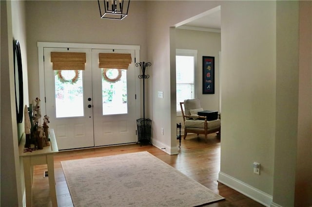 foyer with hardwood / wood-style floors, crown molding, and french doors