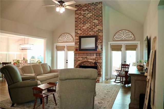 living room featuring french doors, wood-type flooring, high vaulted ceiling, a fireplace, and plenty of natural light