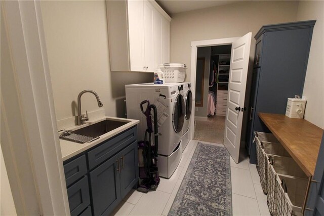 laundry area featuring cabinets, light tile patterned flooring, washer and clothes dryer, and sink