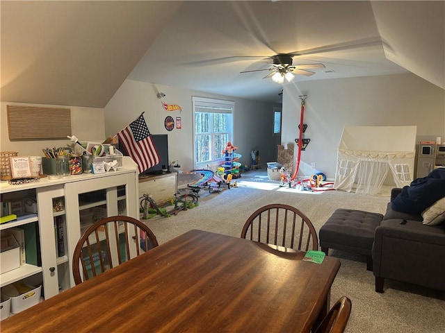 dining area featuring ceiling fan, light colored carpet, and vaulted ceiling