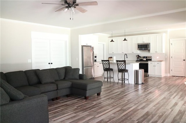 living room featuring ceiling fan, ornamental molding, and hardwood / wood-style flooring