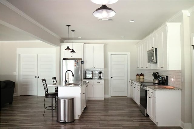 kitchen with tasteful backsplash, a kitchen island with sink, pendant lighting, and appliances with stainless steel finishes