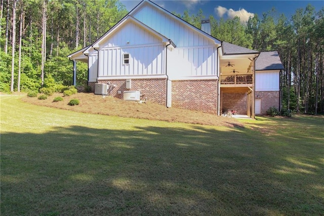 view of side of property with a lawn, ceiling fan, and central AC unit