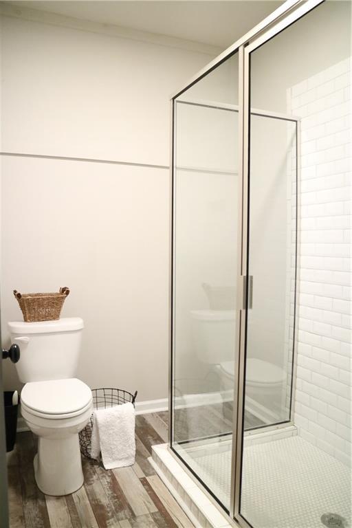 bathroom featuring hardwood / wood-style flooring, toilet, a shower with door, and crown molding