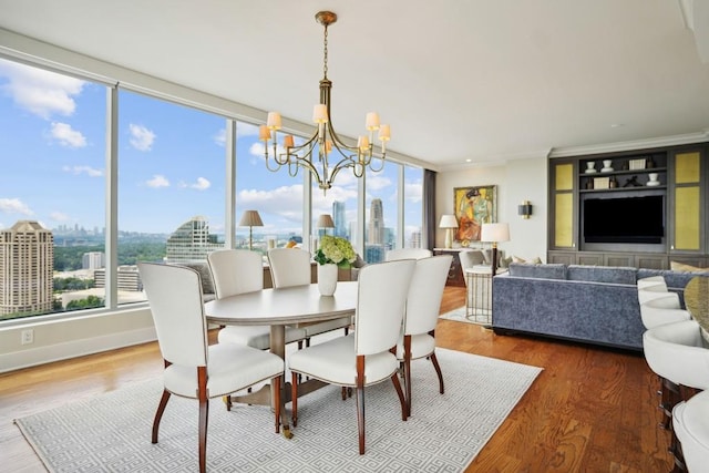 dining area featuring wood finished floors, a wealth of natural light, crown molding, and an inviting chandelier