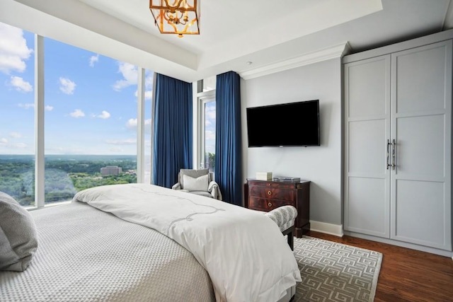 bedroom with baseboards, a notable chandelier, multiple windows, and a raised ceiling