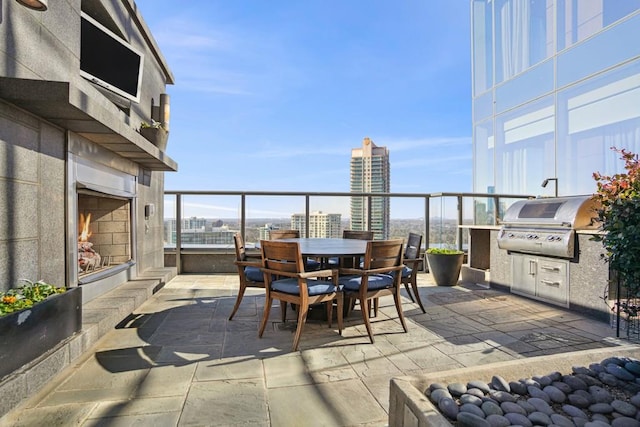 view of patio featuring a city view, outdoor dining space, an outdoor kitchen, and area for grilling
