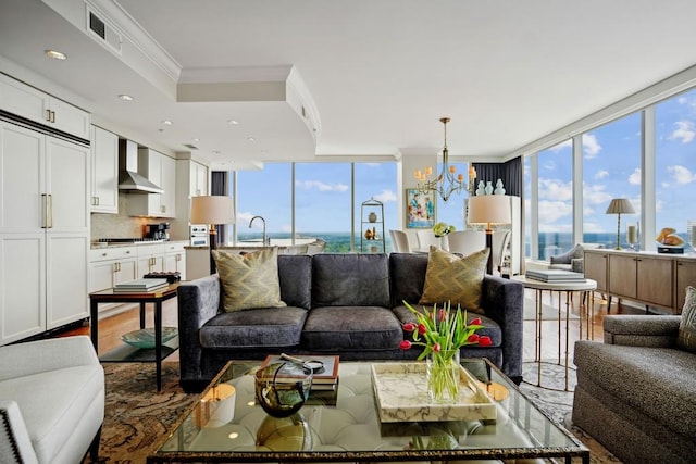 living area featuring a chandelier, visible vents, ornamental molding, and a wall of windows