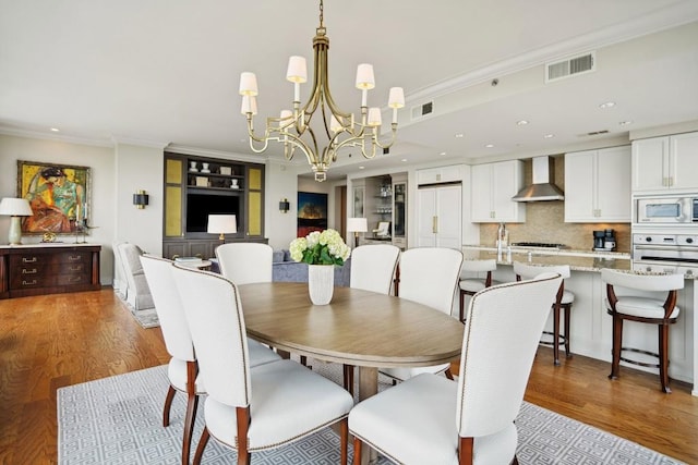 dining space featuring light wood-style flooring, visible vents, recessed lighting, a notable chandelier, and ornamental molding