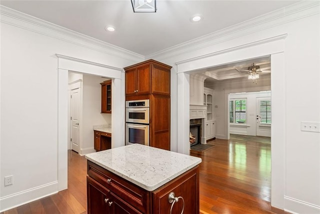 2855 Middlecreek Way Unit 2855, Cumming, GA 30041 - kitchen with stainless steel double oven, ornamental molding, dark wood-type flooring, a fireplace with flush hearth, and baseboards