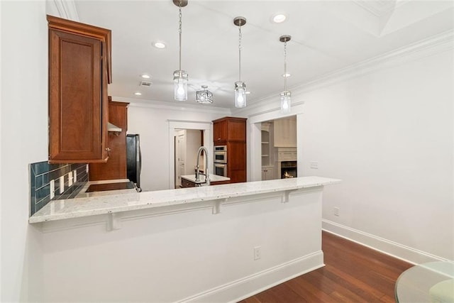 2855 Middlecreek Way Unit 2855, Cumming, GA 30041 - kitchen with a peninsula, brown cabinets, crown molding, dark wood-style floors, and baseboards