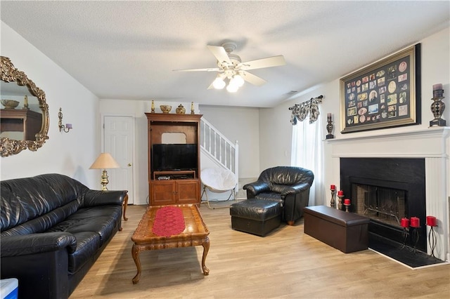 3405 Spring Chase Ln, Ellenwood, GA 30294 - living area featuring light wood-style flooring, ceiling fan, stairs, a fireplace, and a textured ceiling