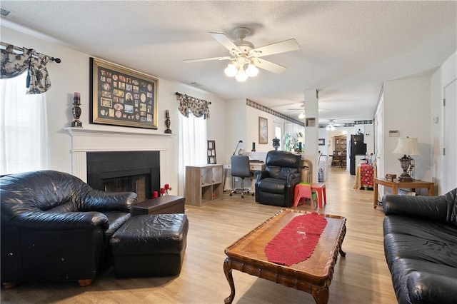 3405 Spring Chase Ln, Ellenwood, GA 30294 - living area featuring ceiling fan, a fireplace with raised hearth, light wood-style floors, and a textured ceiling