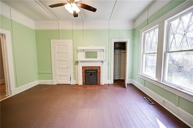 unfurnished living room with a brick fireplace, ornamental molding, ceiling fan, and dark hardwood / wood-style flooring