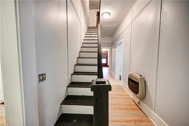 stairway with hardwood / wood-style flooring and heating unit