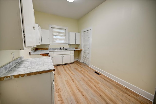 kitchen with sink, white cabinets, and light hardwood / wood-style floors