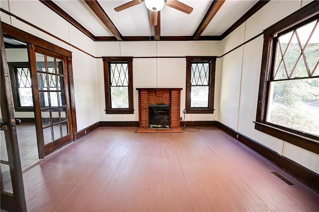 unfurnished living room with a healthy amount of sunlight, beamed ceiling, and hardwood / wood-style flooring