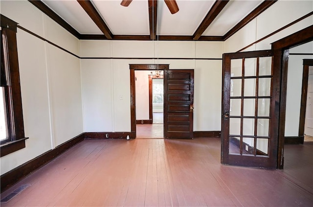 empty room featuring a healthy amount of sunlight, beam ceiling, dark wood-type flooring, and ceiling fan