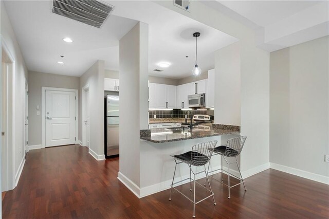 325 E Paces Ferry Rd NE Unit 313, Atlanta, GA 30305 - kitchen with appliances with stainless steel finishes, dark wood-type flooring, decorative backsplash, white cabinetry, and baseboards