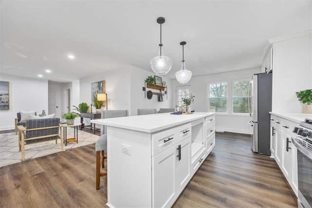 kitchen featuring a breakfast bar, white cabinetry, decorative light fixtures, a kitchen island, and stainless steel appliances