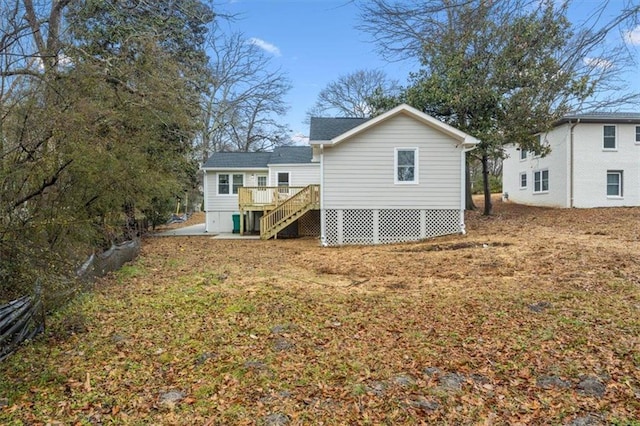 rear view of house featuring a wooden deck and a yard