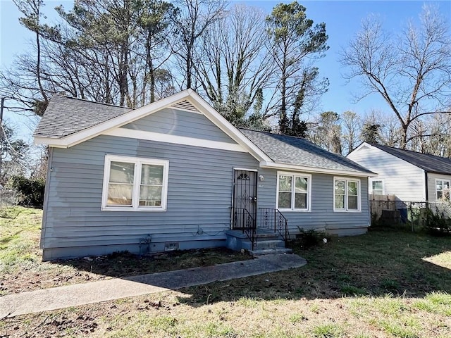 single story home featuring crawl space, a shingled roof, fence, and a front yard