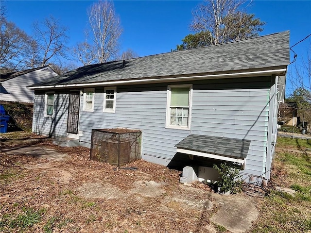 back of house with a shingled roof and entry steps